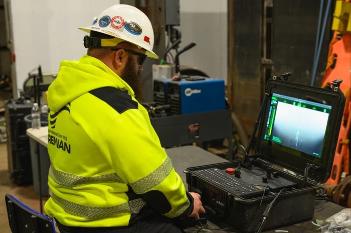 A Brennan crew member monitors a video feed on a portable console during a nuclear refueling outage.
