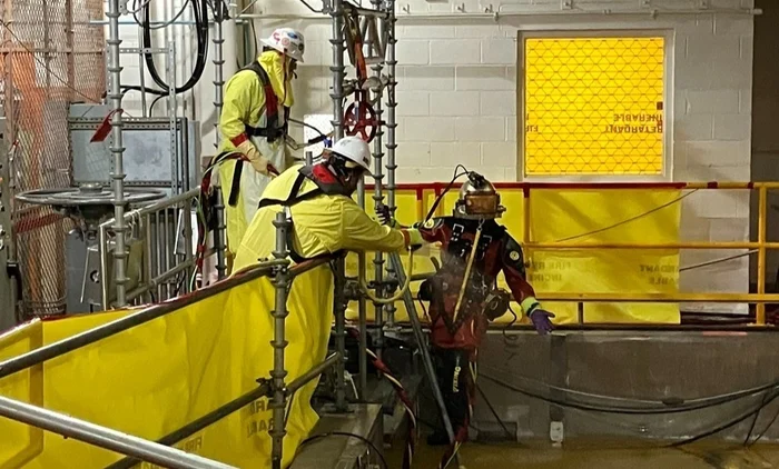 Brennan crew members assist a commercial diver during a nuclear refueling outage near a water tank.