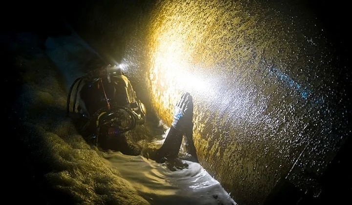 A Brennan dive crew inspects a large submerged pipe during a nuclear refueling outage.