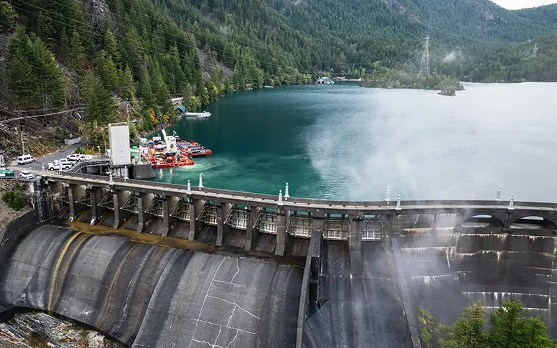 Brennan crew operating a crane on a barge near a dam spillway.