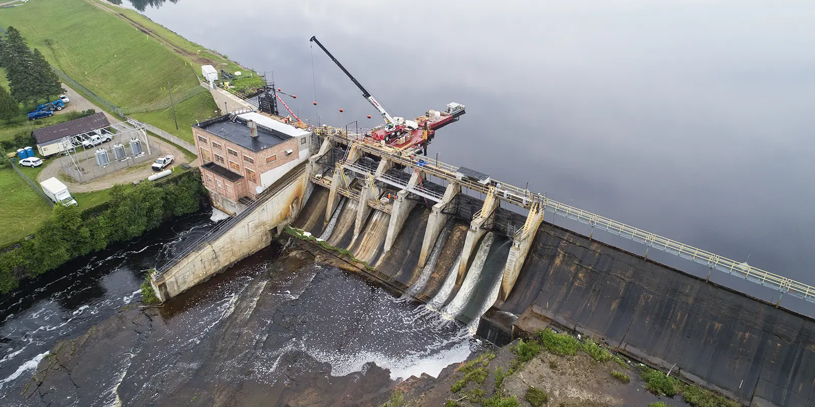 A Brennan crew operates a crane on a barge at a dam spillway.